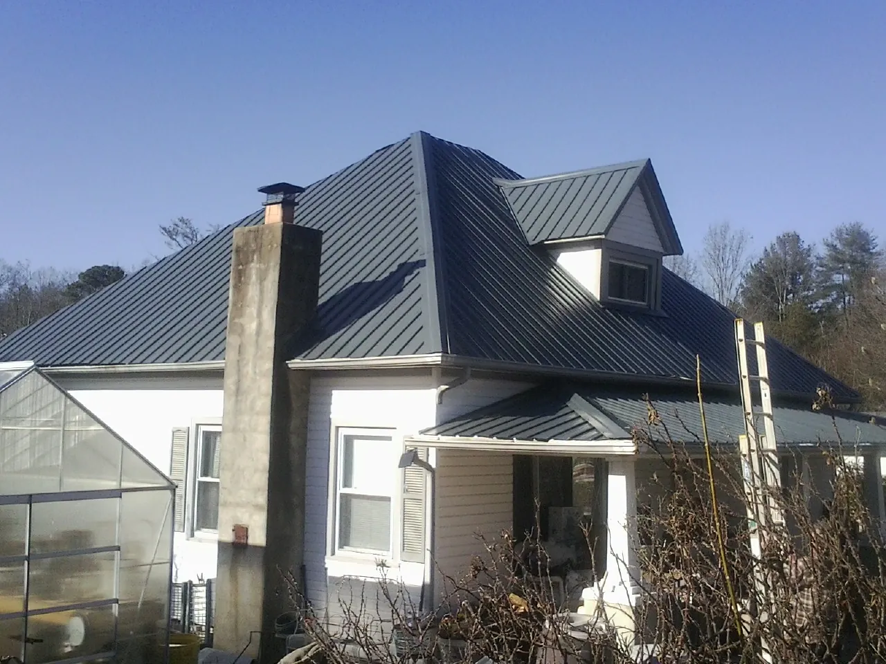Dark blue standing seam metal roof on a white farmhouse with dormer — Slate & Tile Roof Repair by Roofing Brothers in Thorofare