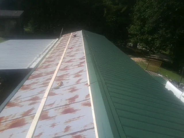 Old rusted panels beside newly installed green metal roofing — Wind Damage Roof Repair by Roofing Brothers in Thorofare
