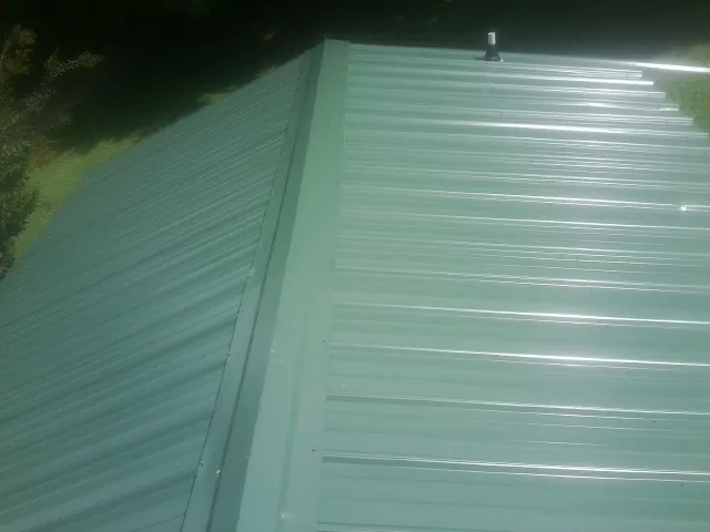 New green metal panels meeting at the ridge of a roof — Flat Roof Repair work by our crew in Thorofare