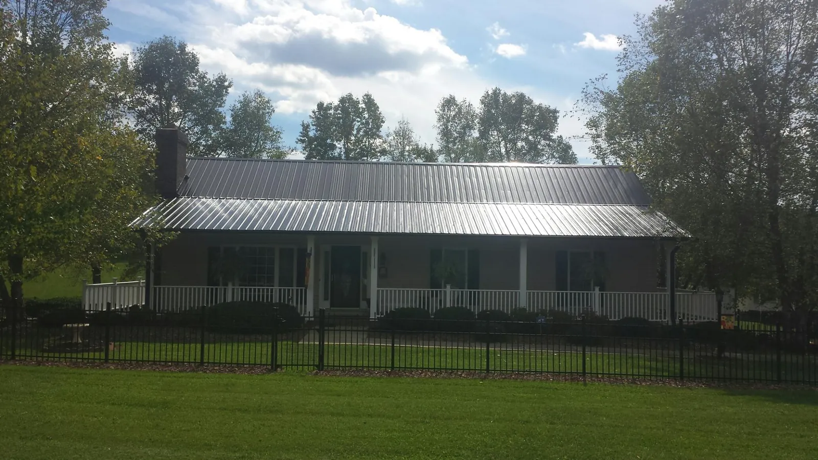Gray metal roof on a brick ranch with a full width front porch — Gutter Guard Installation work by our crew in Thorofare