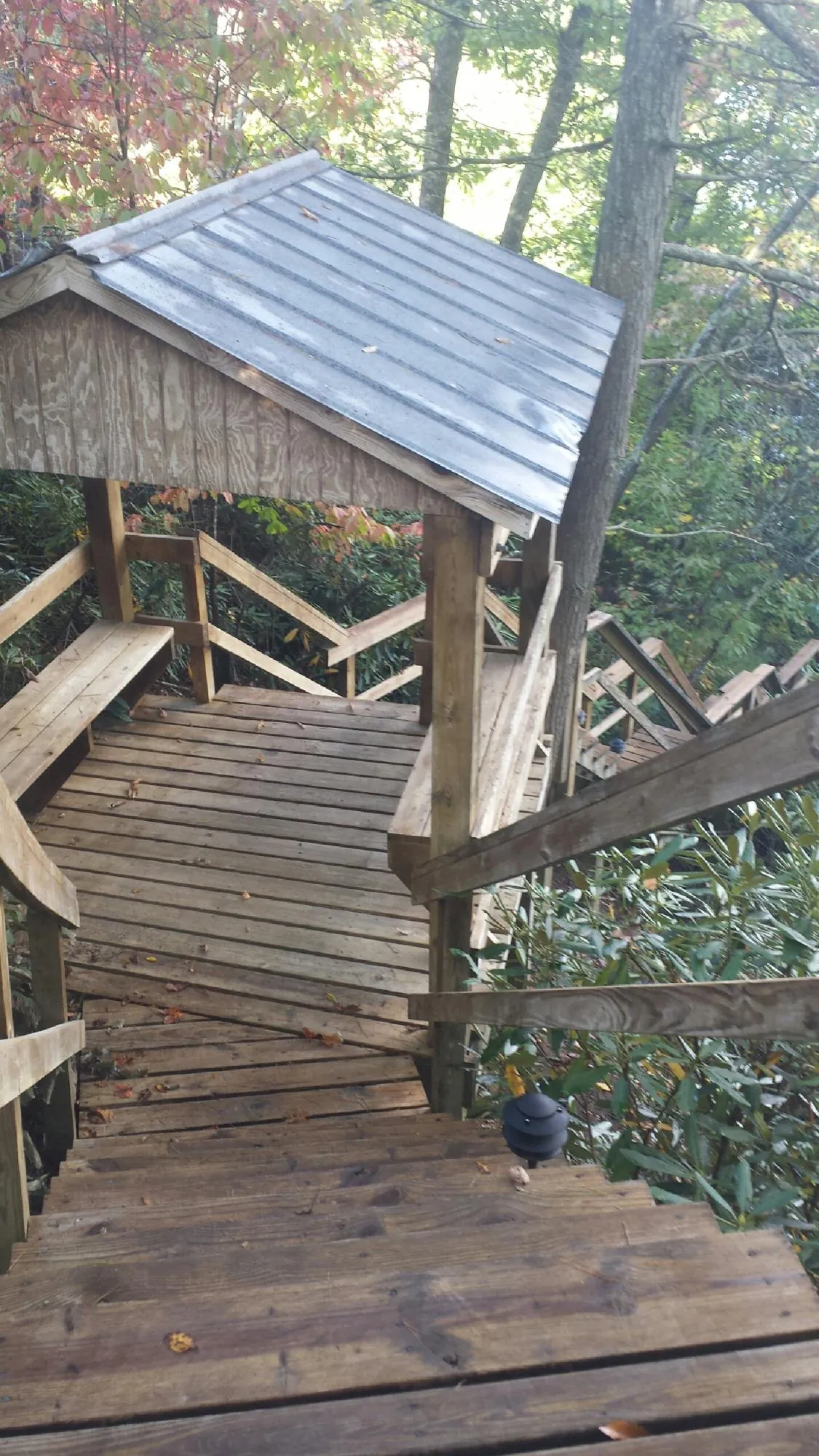 Metal roofed shelter over wooden steps on a wooded walkway — Skylight Repair & Installation work by our crew in Thorofare