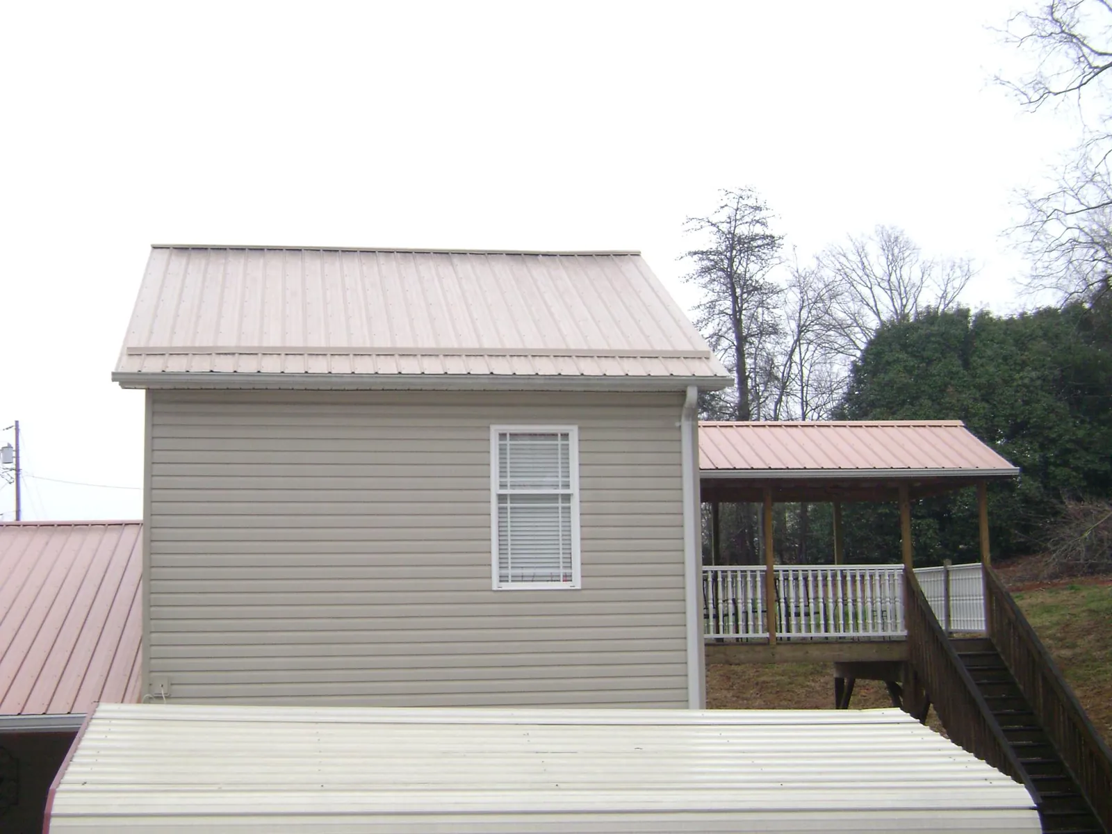 Tan metal roofs on a two story addition and attached porch, from a Roof Replacement job in Thorofare