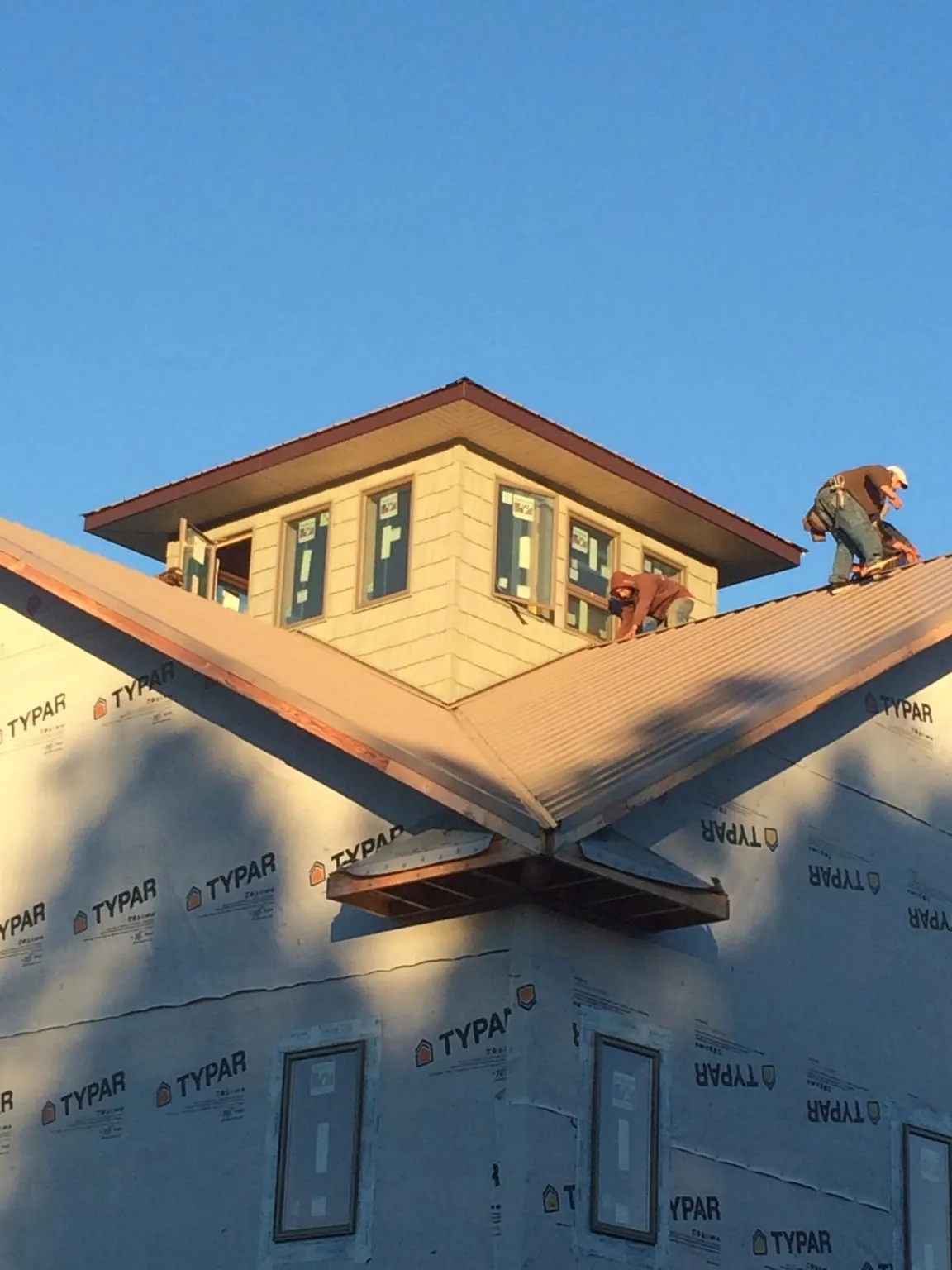 Roofers working around a rooftop cupola on a new metal roof at sunset — Roof Waterproofing in Thorofare by Roofing Brothers